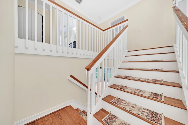 staircase featuring wood-type flooring and ornamental molding