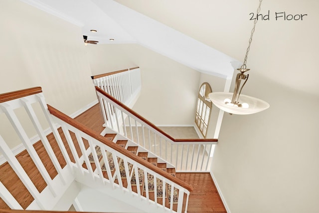 stairway with vaulted ceiling and hardwood / wood-style floors