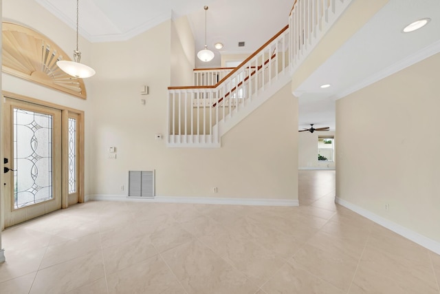 foyer entrance featuring ceiling fan, a towering ceiling, ornamental molding, and light tile patterned floors