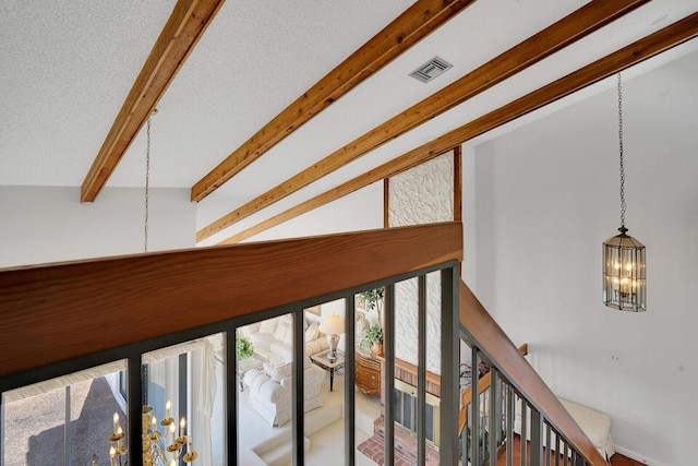 hall featuring a notable chandelier, a textured ceiling, and vaulted ceiling with beams