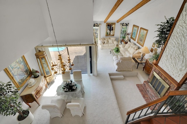 living room with a notable chandelier, beamed ceiling, and a brick fireplace