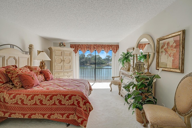 carpeted bedroom with a water view, access to exterior, and a textured ceiling