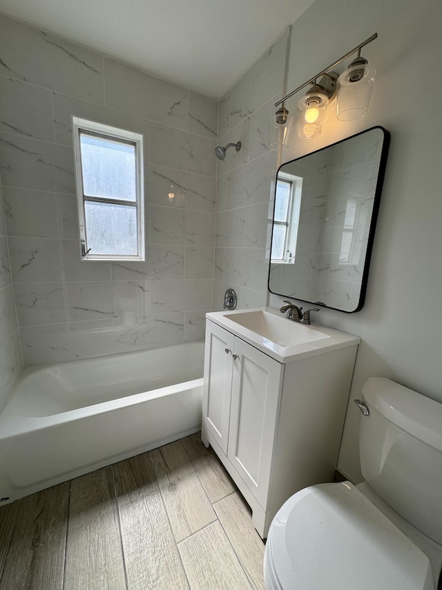 full bathroom featuring vanity, tiled shower / bath combo, wood-type flooring, and toilet