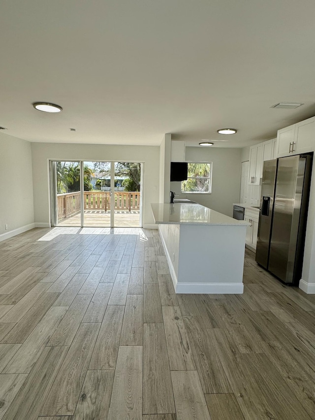 kitchen with light hardwood / wood-style floors, stainless steel fridge with ice dispenser, and white cabinets