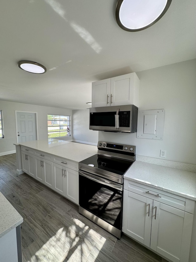 kitchen featuring hardwood / wood-style floors, light stone countertops, white cabinets, and appliances with stainless steel finishes