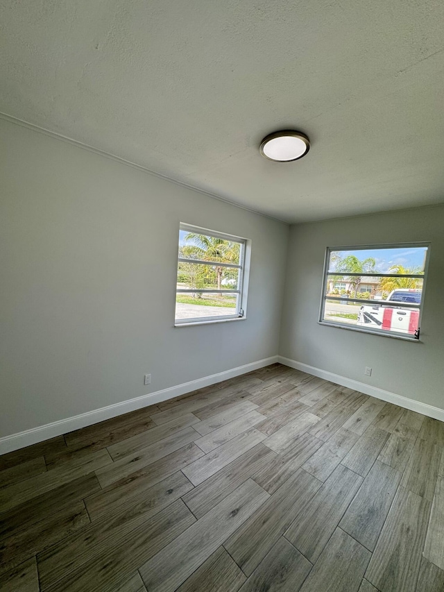 spare room with light hardwood / wood-style flooring and a textured ceiling