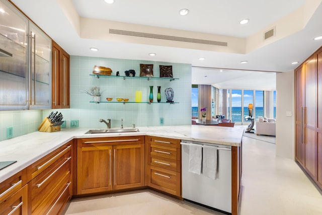 kitchen with light stone counters, stainless steel dishwasher, sink, and backsplash