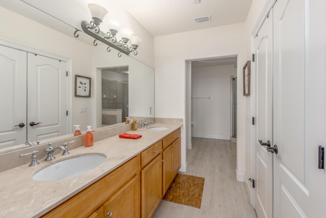 bathroom featuring vanity, wood-type flooring, a textured ceiling, and walk in shower