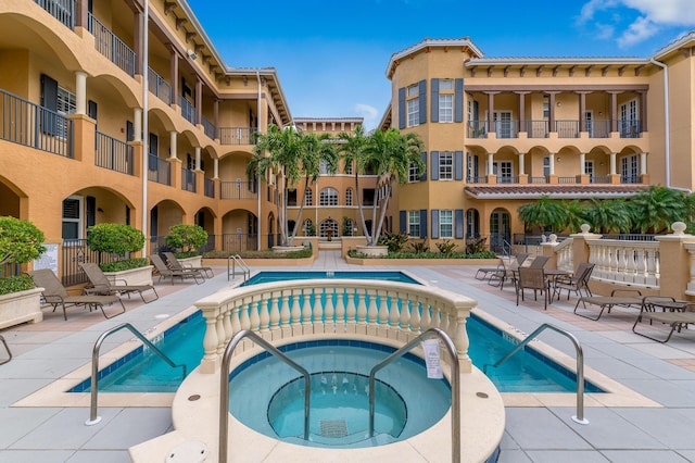 view of swimming pool featuring a hot tub and a patio