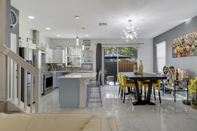 kitchen with pendant lighting, white cabinetry, stainless steel appliances, a kitchen island, and wall chimney exhaust hood