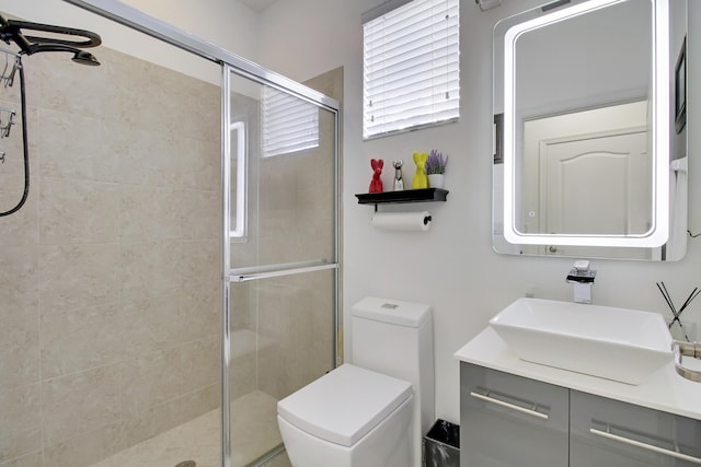 bathroom featuring vanity, toilet, and a shower with shower door