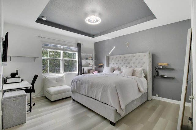bedroom featuring a tray ceiling and light hardwood / wood-style floors