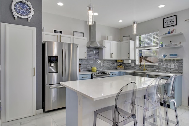 kitchen with wall chimney exhaust hood, a kitchen bar, white cabinetry, appliances with stainless steel finishes, and a kitchen island
