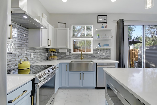 kitchen with wall chimney range hood, sink, appliances with stainless steel finishes, white cabinetry, and decorative backsplash