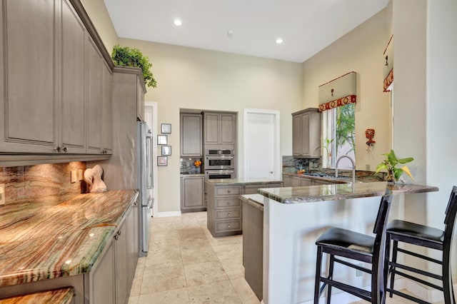 kitchen featuring a kitchen bar, a kitchen island, kitchen peninsula, and stone countertops