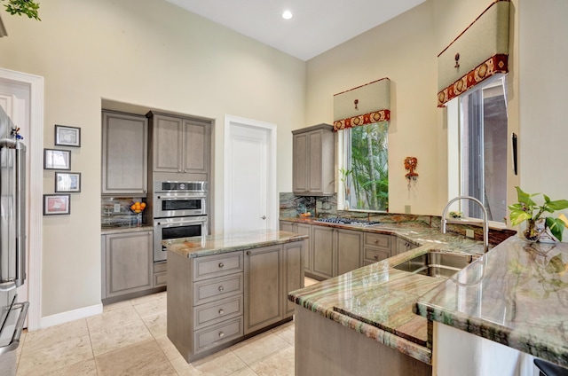 kitchen with light stone counters, sink, tasteful backsplash, and kitchen peninsula