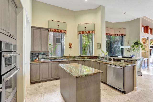 kitchen with light stone counters, a center island, appliances with stainless steel finishes, and kitchen peninsula