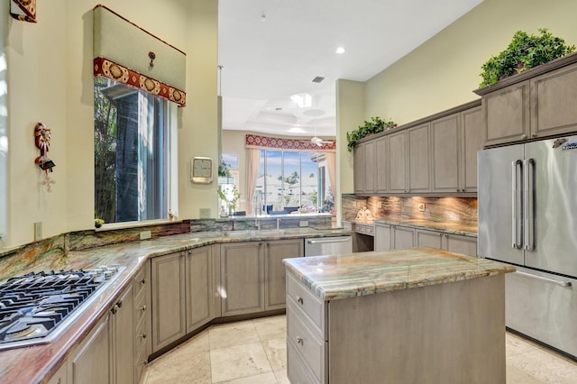 kitchen featuring sink, tasteful backsplash, appliances with stainless steel finishes, a raised ceiling, and a kitchen island