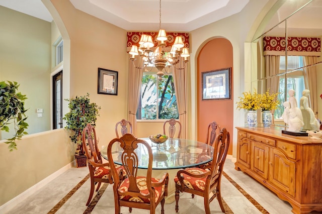 dining area featuring a notable chandelier and a raised ceiling