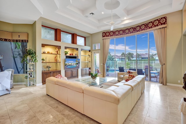 living room with built in shelves, ceiling fan, coffered ceiling, and a high ceiling