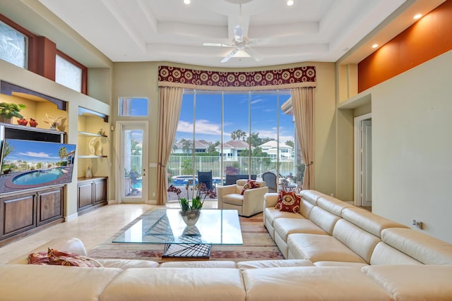 living room featuring a towering ceiling, built in features, and ceiling fan