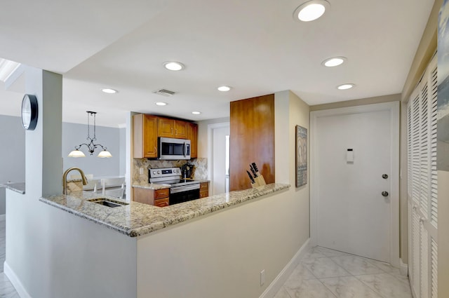 kitchen with stainless steel appliances, decorative light fixtures, light stone counters, and kitchen peninsula