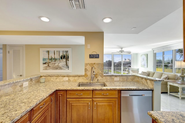 kitchen featuring tasteful backsplash, dishwasher, sink, light stone counters, and kitchen peninsula