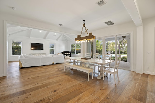 dining space featuring vaulted ceiling with beams, a wealth of natural light, and light hardwood / wood-style floors