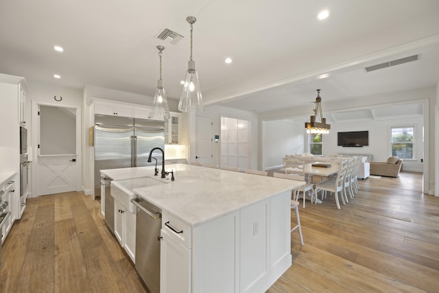 kitchen featuring white cabinetry, stainless steel appliances, and an island with sink