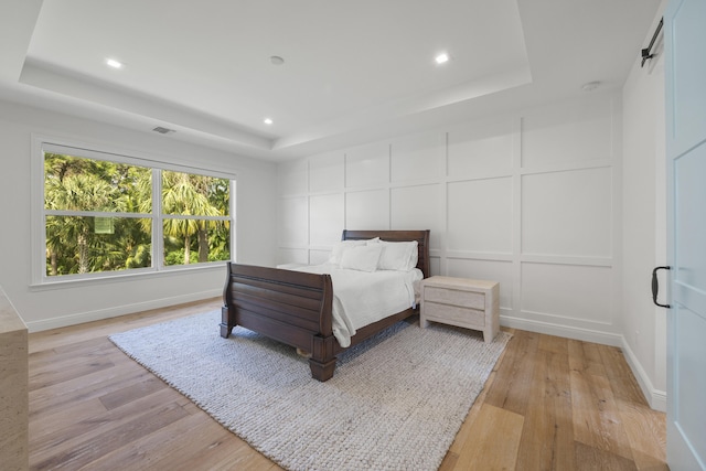 bedroom featuring light hardwood / wood-style flooring and a tray ceiling