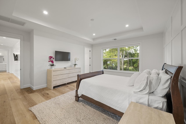 bedroom featuring a tray ceiling and light hardwood / wood-style floors