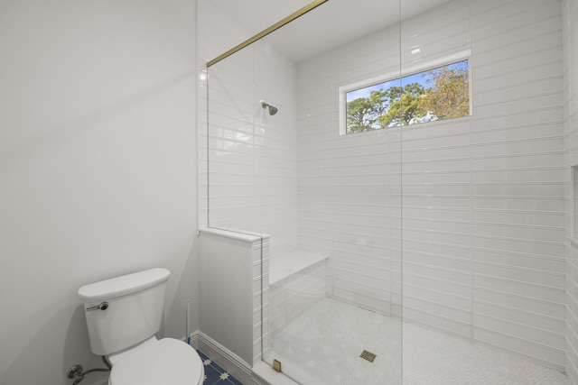 bathroom with a tile shower and toilet