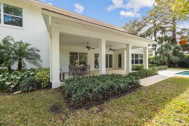 rear view of property with ceiling fan and a patio area