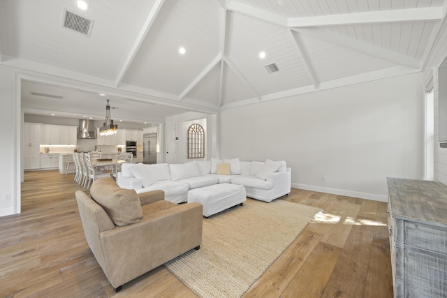 living room with beamed ceiling, high vaulted ceiling, and light hardwood / wood-style flooring