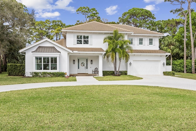 view of front of house with a garage, a front yard, and covered porch