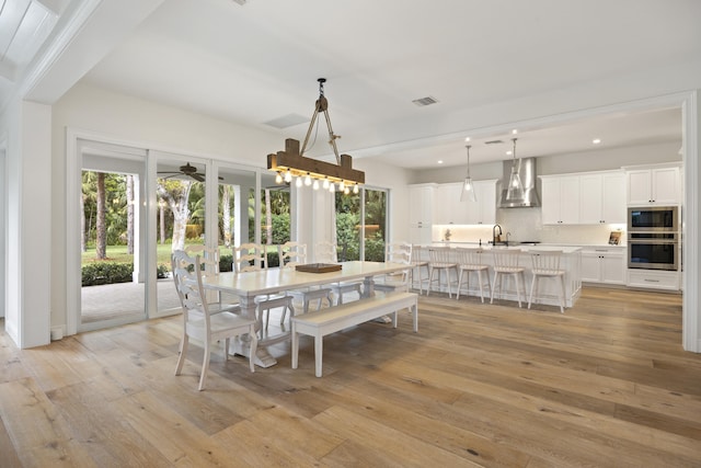 dining area featuring ceiling fan, a healthy amount of sunlight, sink, and light wood-type flooring