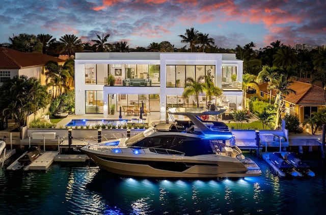 rear view of house with a patio area, boat lift, a water view, and a community pool