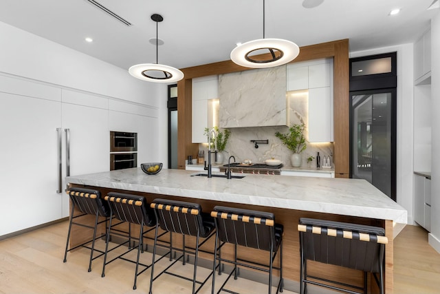 kitchen with white cabinets, modern cabinets, tasteful backsplash, and light wood finished floors