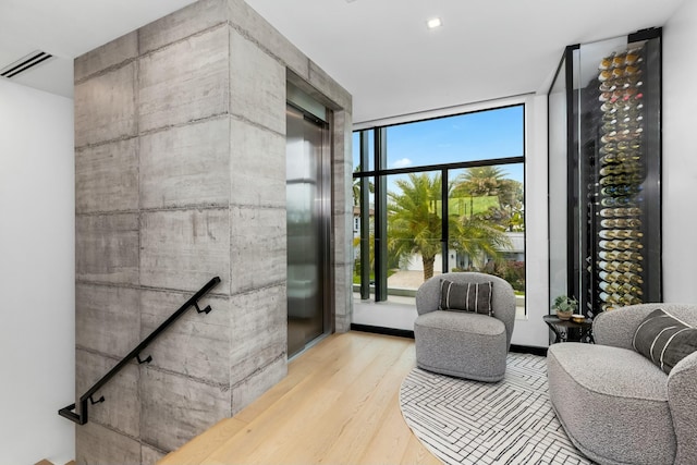 sitting room featuring visible vents, elevator, and wood finished floors