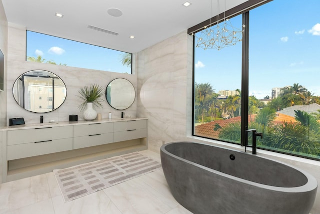 full bath featuring visible vents, double vanity, a soaking tub, a sink, and tile walls