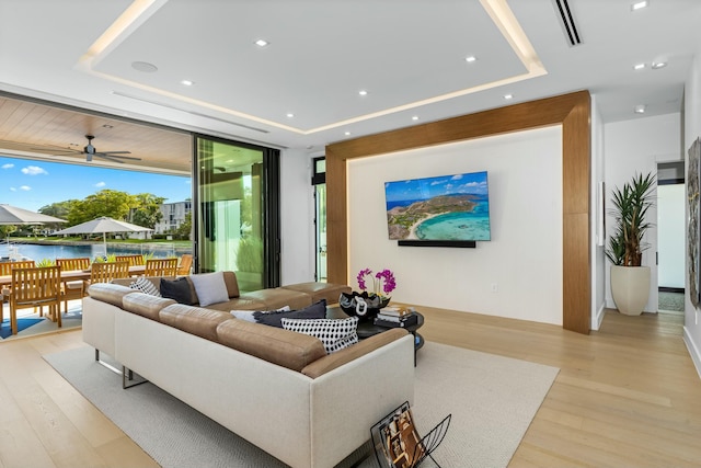 living area featuring light wood-type flooring, a raised ceiling, and visible vents