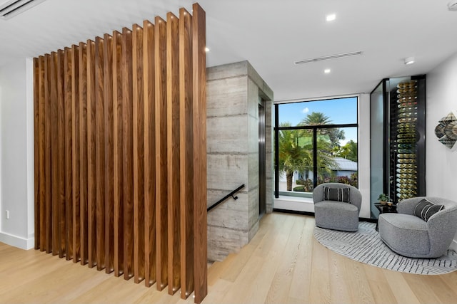 living area with floor to ceiling windows, wood finished floors, and visible vents