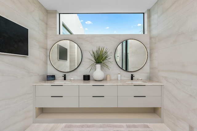 bathroom with double vanity, tile walls, and a sink