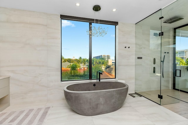 bathroom with tile walls, a freestanding tub, and a shower stall