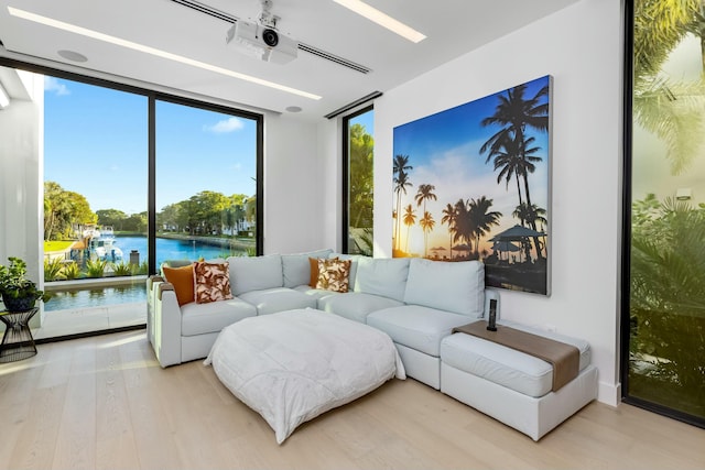 living room with a ceiling fan, a wall of windows, wood finished floors, and a water view