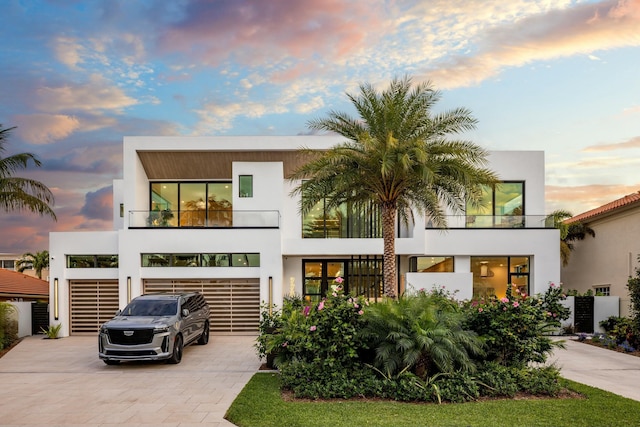 contemporary home with stucco siding, decorative driveway, and a garage