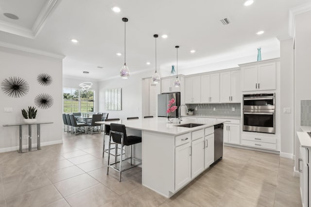 kitchen with sink, crown molding, a kitchen island with sink, white cabinetry, and stainless steel appliances