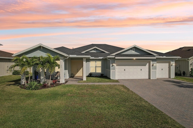 ranch-style home featuring a garage and a lawn