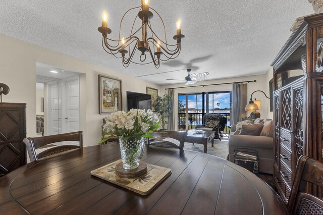 dining area featuring ceiling fan with notable chandelier and a textured ceiling