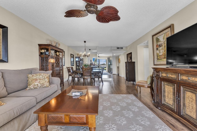 living room with hardwood / wood-style flooring, ceiling fan with notable chandelier, and a textured ceiling